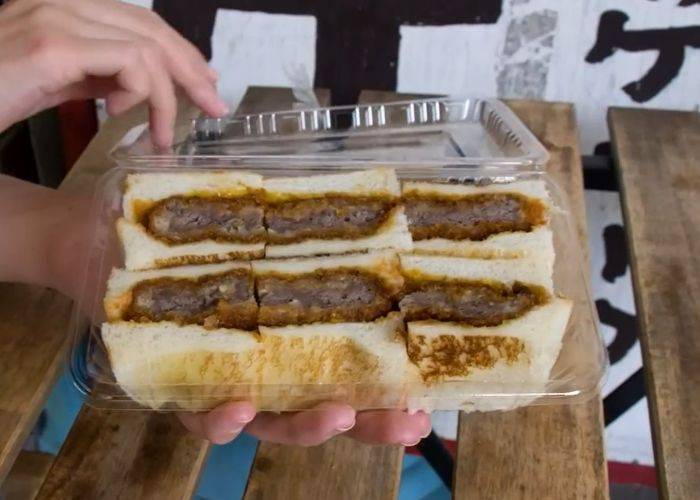 The juicy beef and crispy bread of a beef katsu sandwich street food vendor in Osaka.